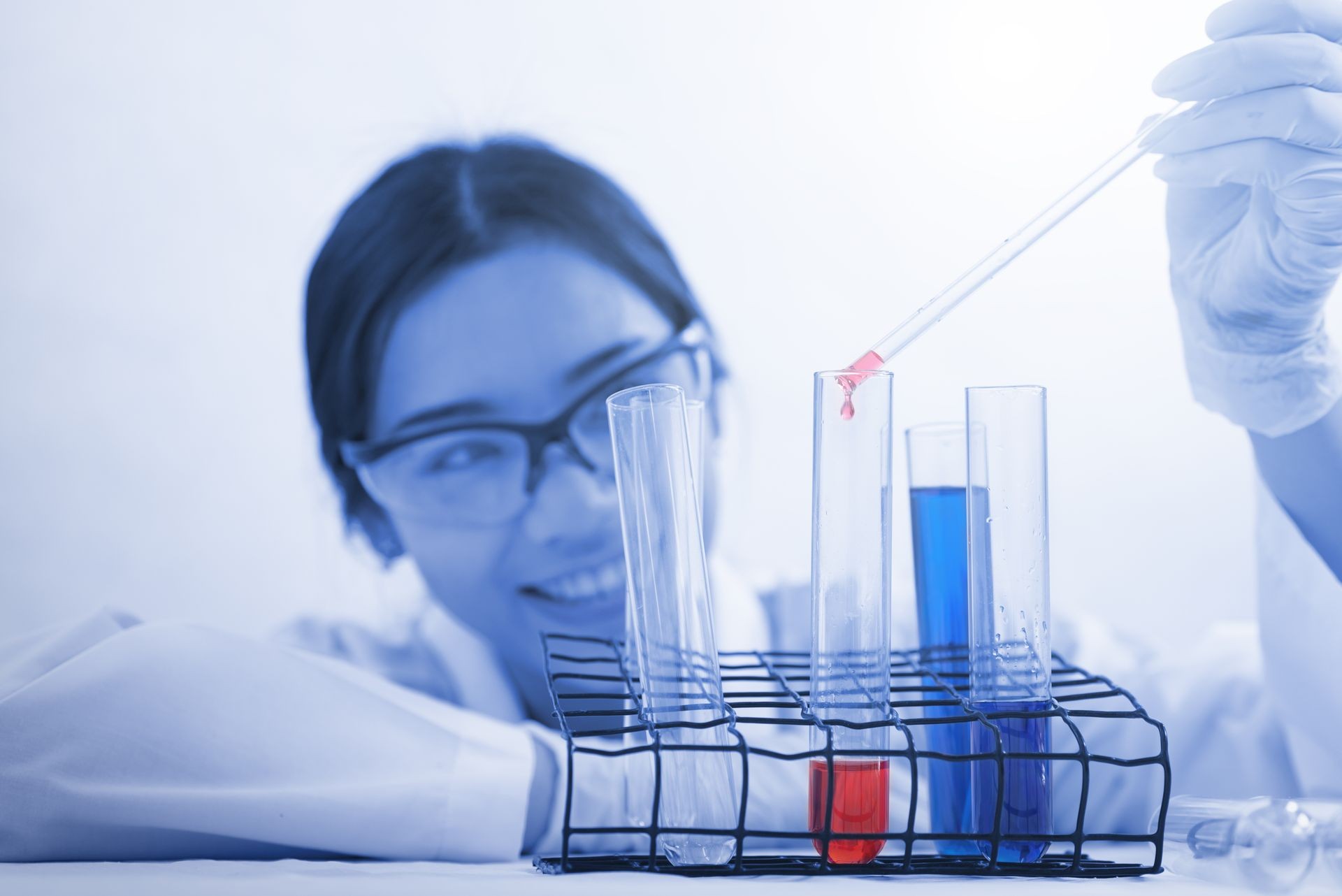 Young women scientists are interested in and dripping red chemicals in glass and have a blue glass of glass around in a forensic laboratory. New Scientist Concept Double exposure.